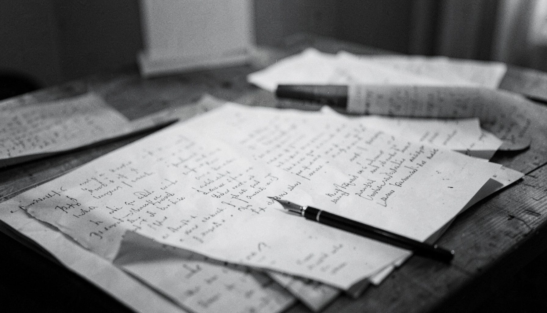 A quiet writing desk with scattered manuscript pages and a fountain pen in soft grayscale lighting, contemplative mood